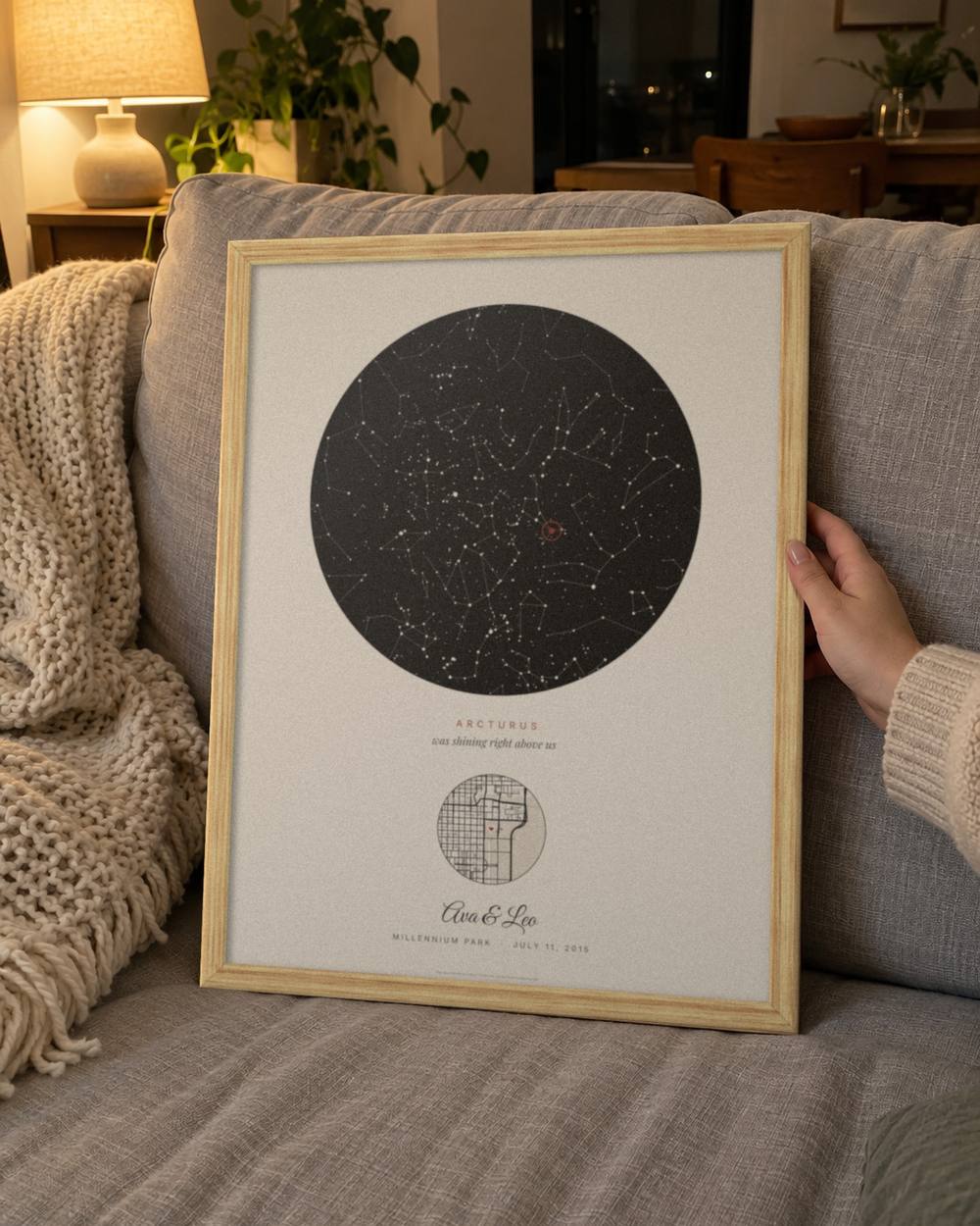 Anniversary star map held up on a gray sofa in a light oak frame, an example: Our star in Cream with Arcturus circled, the sky over Millennium Park in Chicago on the proposal night of Ava & Leo