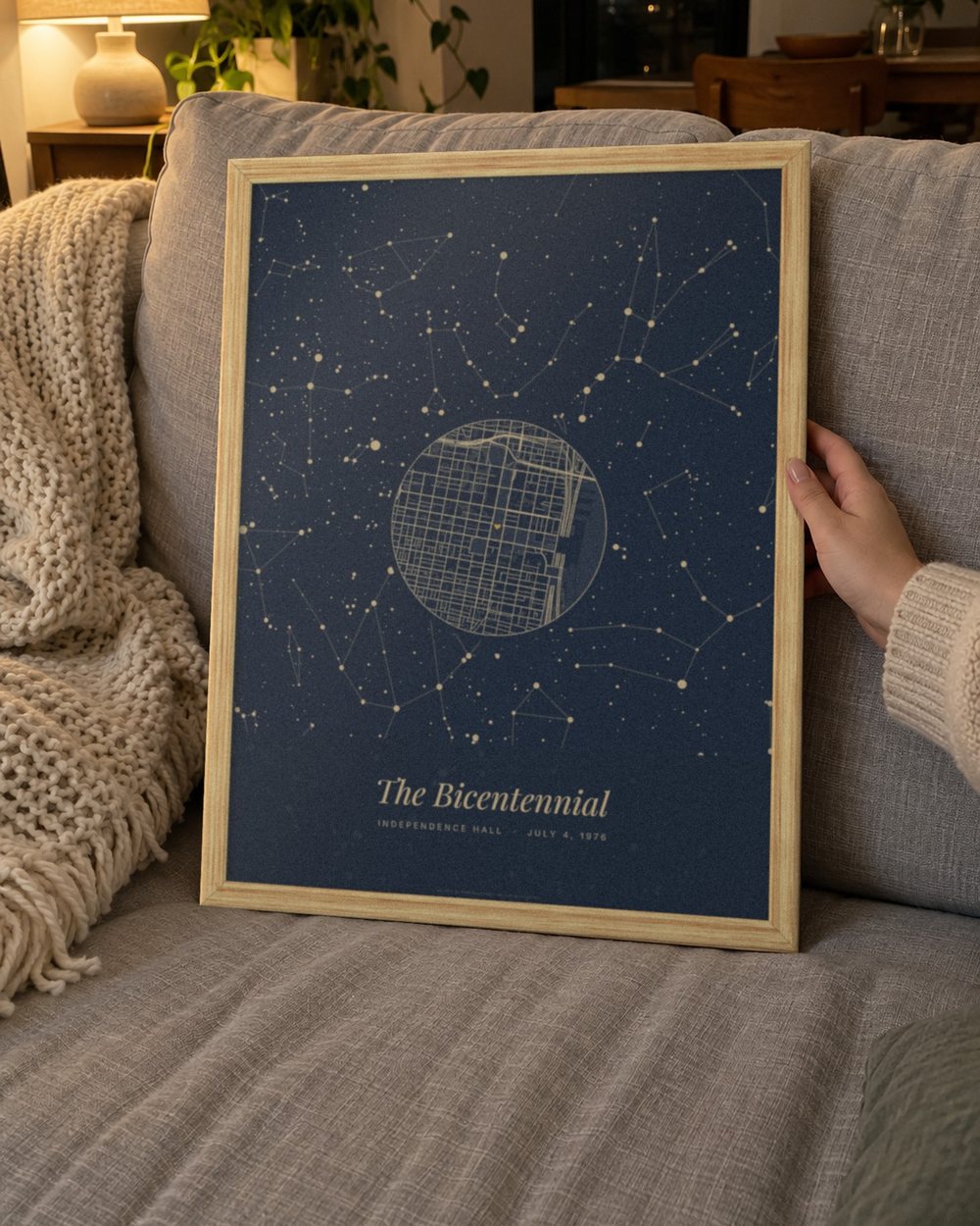Star map poster in an oak frame held on a sofa: the sky over Independence Hall, Philadelphia on July 4, 1976 in The whole night design, Navy, with the line The Bicentennial