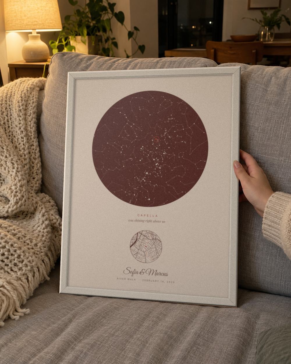 Valentine's Day star map in a white frame held on a sofa, an example: Our star in Blush for the River Walk, San Antonio, February 14, 2020, Capella circled, names Sofia & Marcus